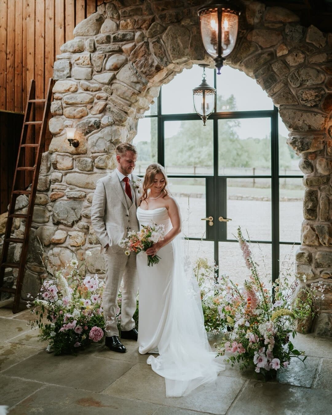 Lucy and Sam in a stone archway dressed with flowers at Willow Marsh Farm